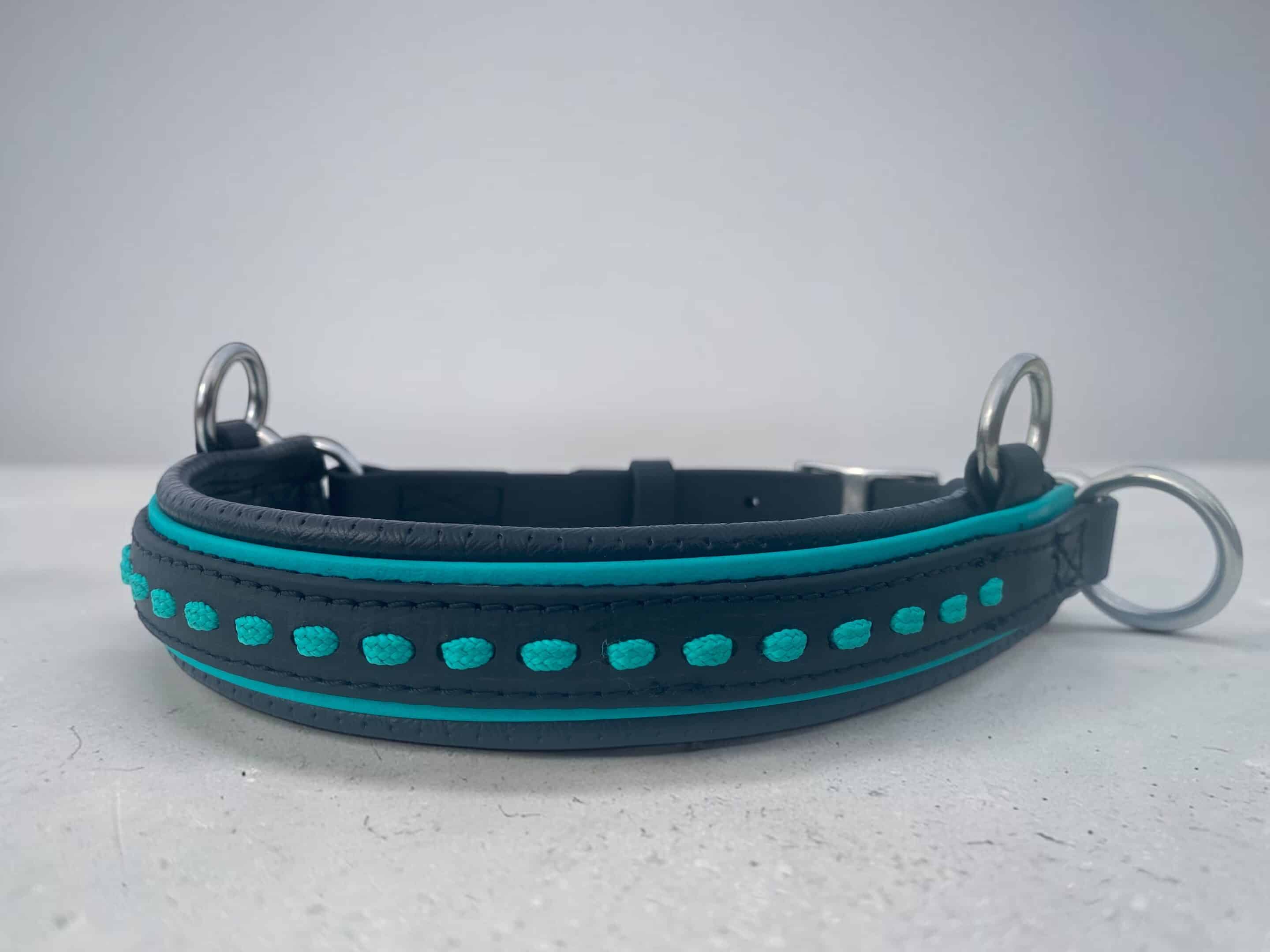 LacedSPAttach | Madtack Close-up of a black dog collar with turquoise stitching and metal D-rings on a light surface.